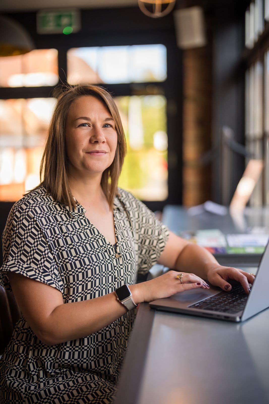 Leanne Terry working at a laptop by a tall window