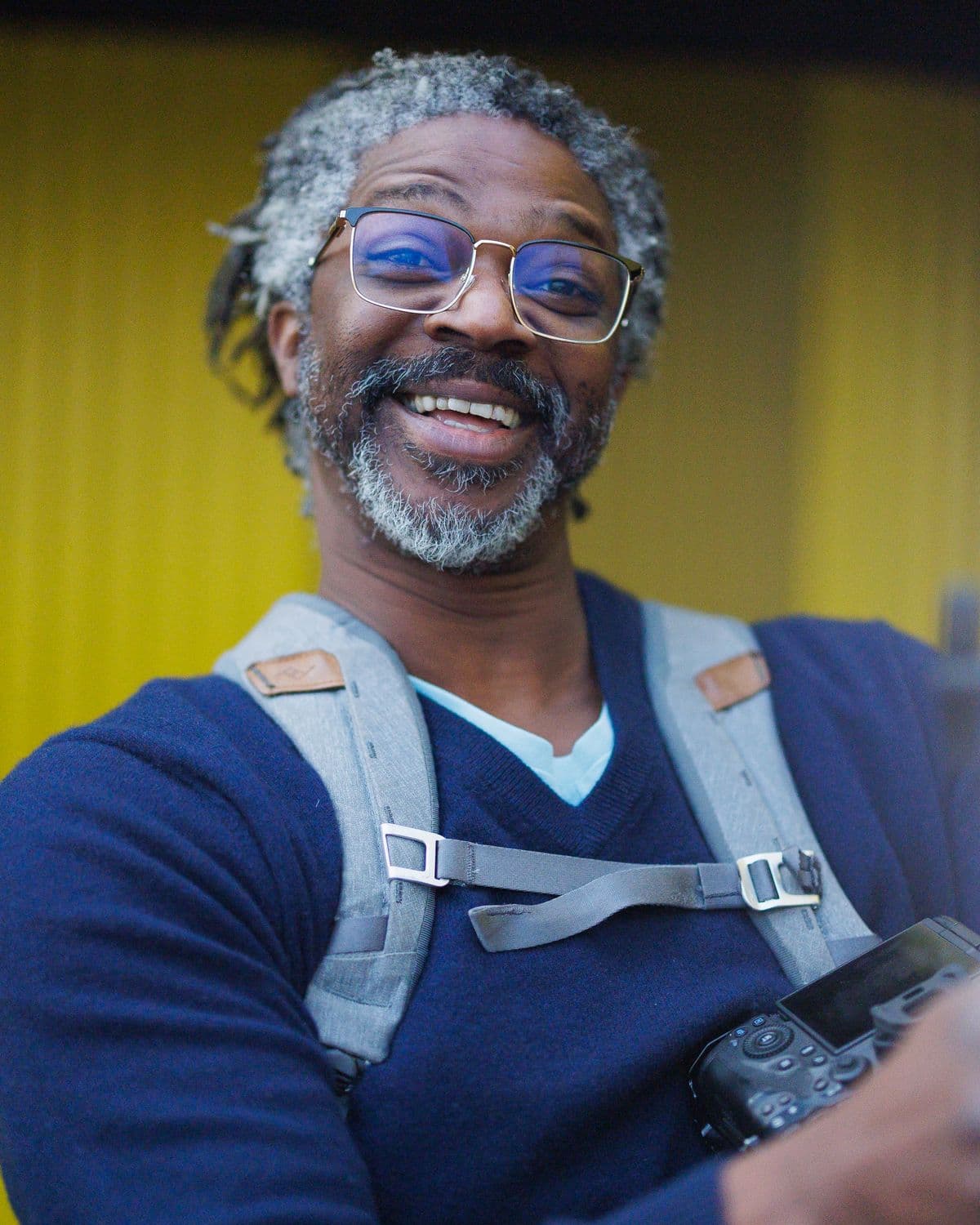 Kevan smiling at the camera with a camera on his harness and a light beside him, on the day of Jon's headshots, January 2024