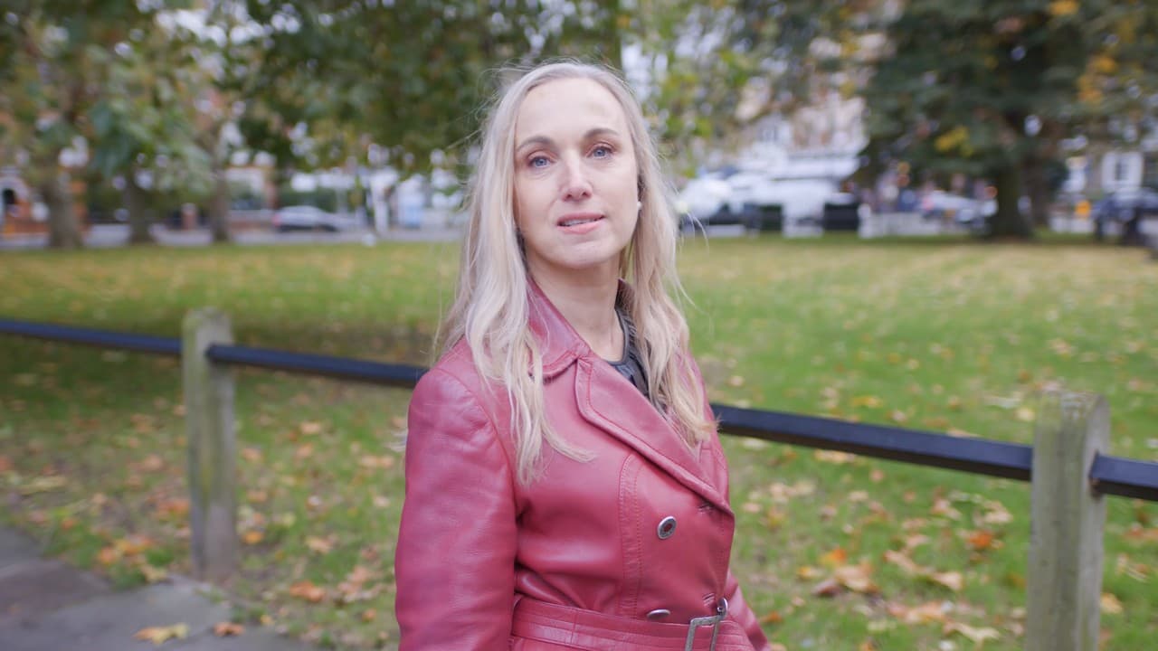 Helene in her red leather coat on a green, looking to the camera, in her film about becoming a coach