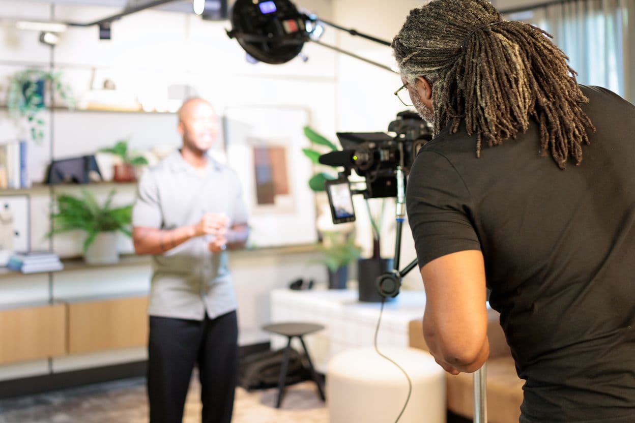 Kevan behind a camera on a stand, Undray standing on his mark under the lights, on the May 2026 filming day