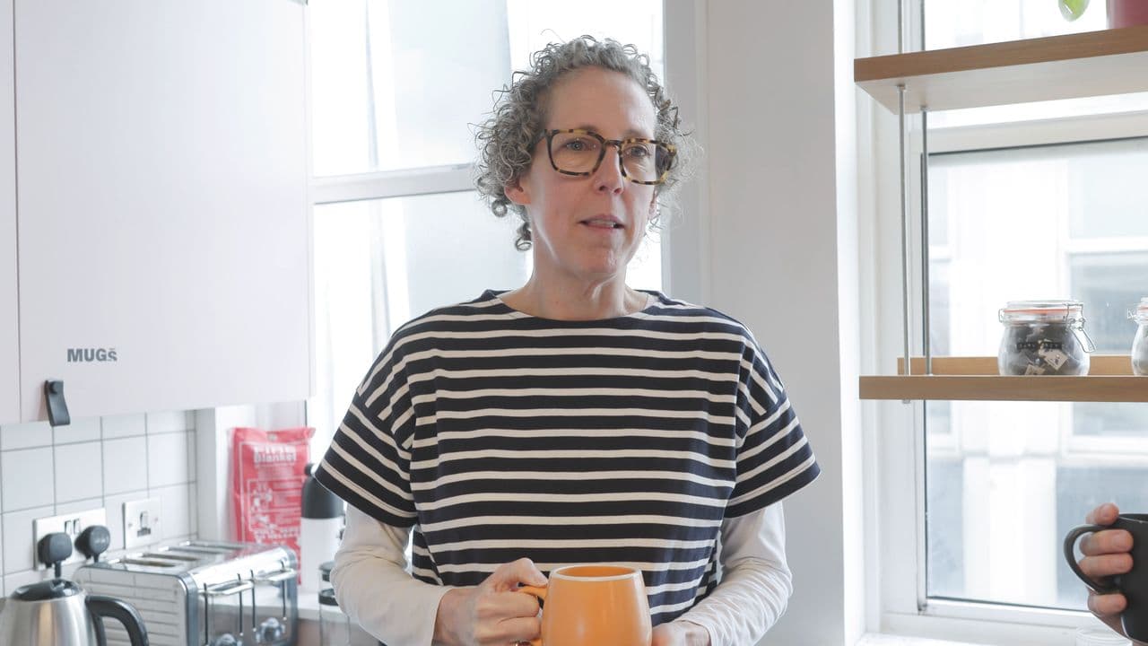 Alex speaking to the camera in the Platf9rm kitchen, orange mug in hand