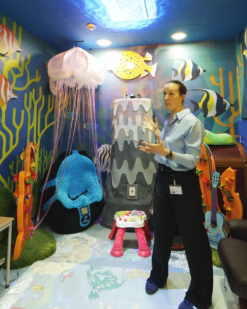 Donna Holland in the hospital's sensory room, with a jellyfish lamp, painted fish and a beanbag