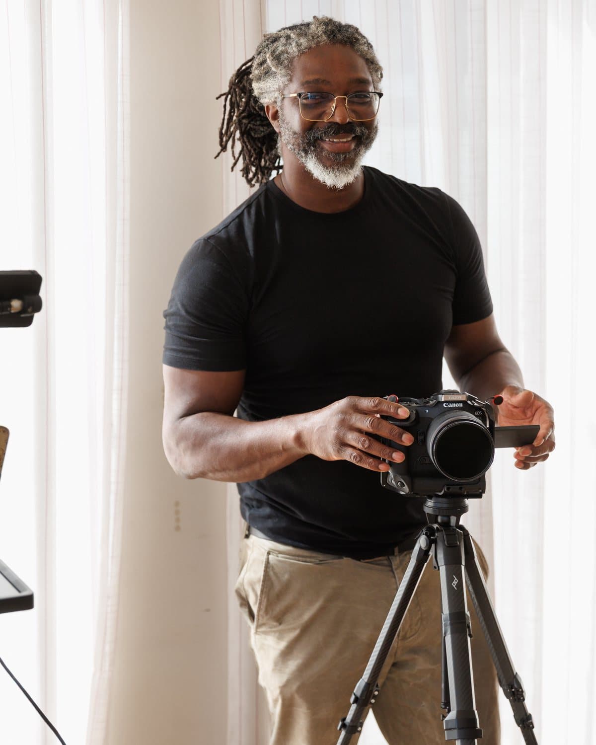 Kevan Smith, founder of Epiphany Content, smiling at the lens with his hands on a camera, a teleprompter rig beside him